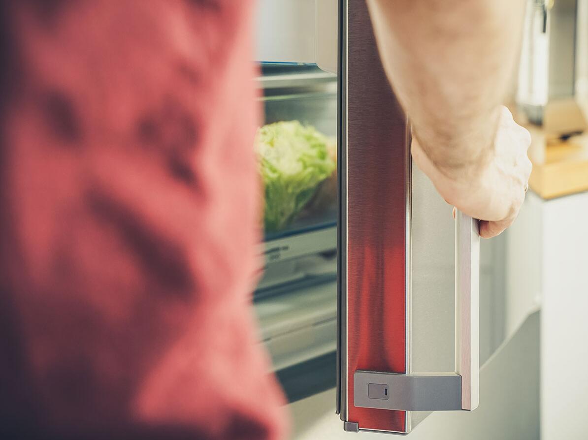 Mand står foran køleskab og prøver at spare på brugen