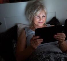 Kvinde læser E-bog på sin tablet men skærmen kan skade hendes søvn. t 