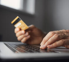 Person sidder med computer og betalingskort