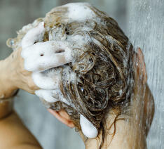 Kvinde vasker shampoo ud af håret