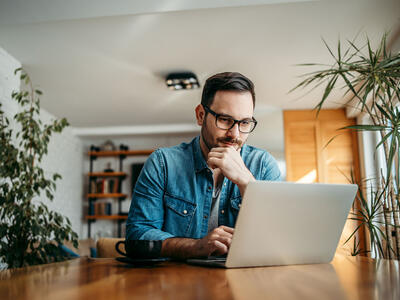 Mand der sidder og kigger på sin laptop og skal finde ud af hvilket mærke indenfor computer han skal vælge
