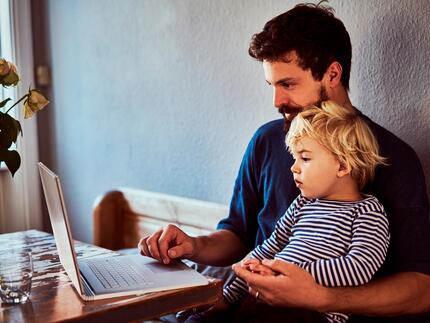 Far sidder med sit barn og kigger på dets børneopsparing på nettet