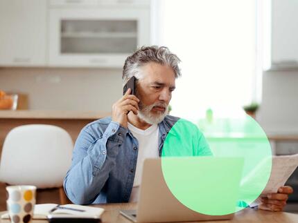 mand med computer og telefon