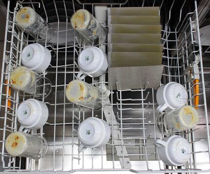 Opvaskemaskine fyldt med beskidte glas, kopper og plader til test af opvasketabs