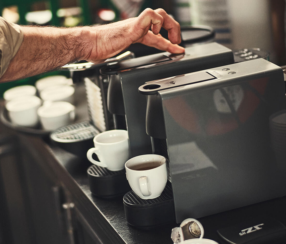 Person gør brug af kaffemaskiner for at teste kaffekapsler