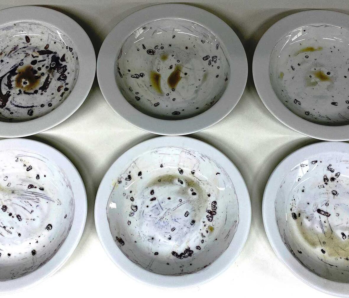 Tallerkener med indtørret havegrød farvet efter test af opvasketabs