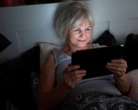 Kvinde læser E-bog på sin tablet men skærmen kan skade hendes søvn. t 