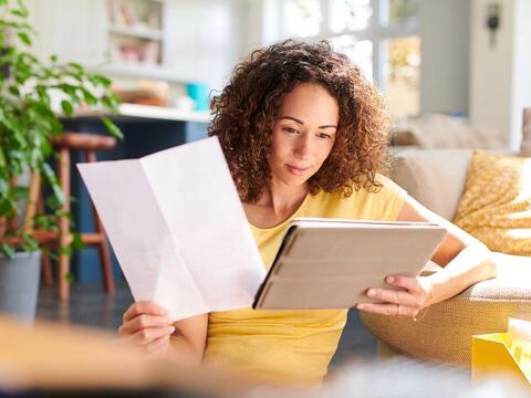 kvinde kigger på papir og tablet med informationer om en investerinsforening