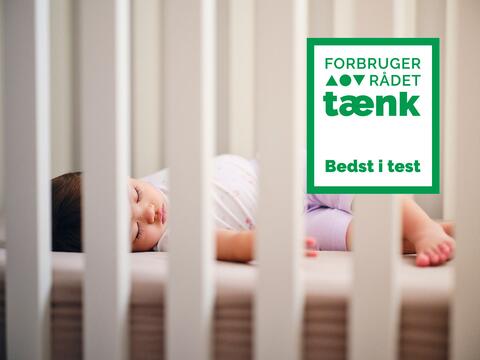 Barn sover på madras i tremmeseng - illustrerer test af babymadrasser