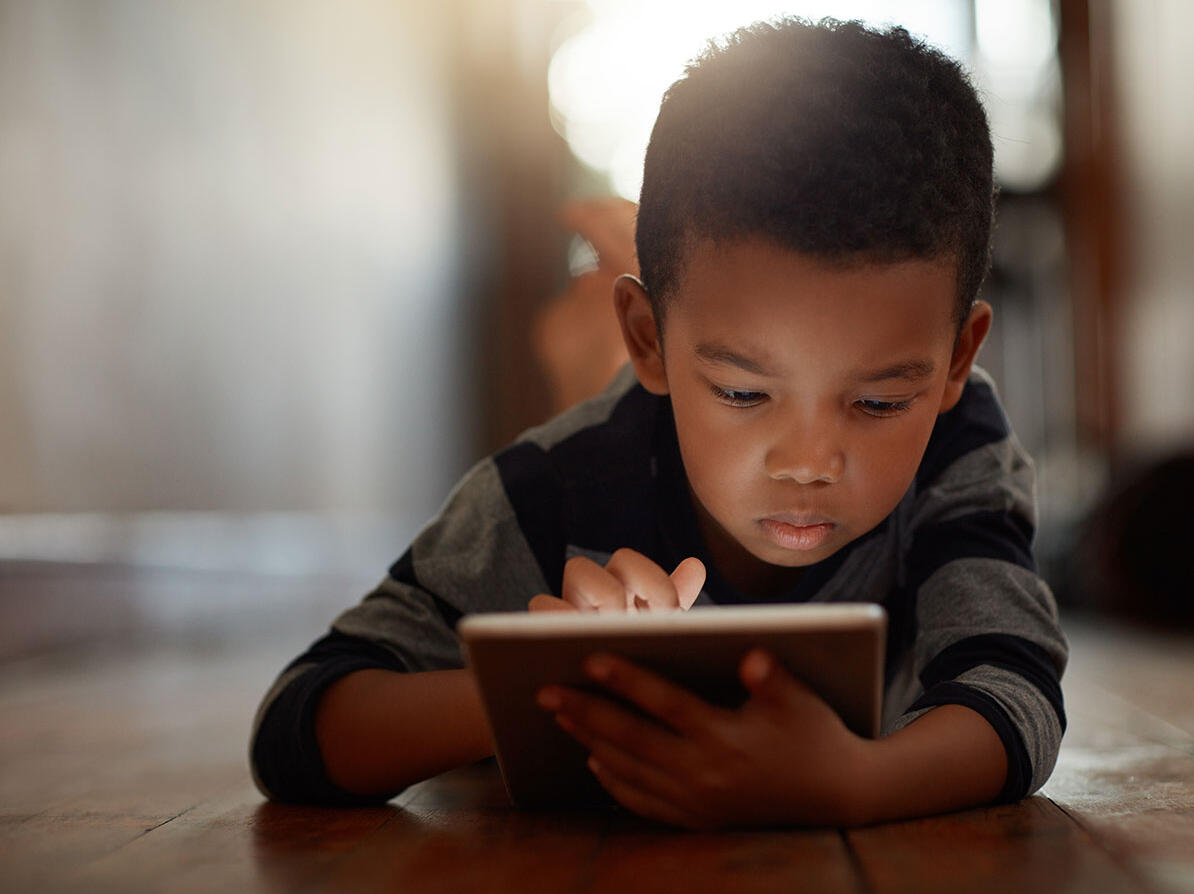 Barn der kigger på en tablet og er på nettet