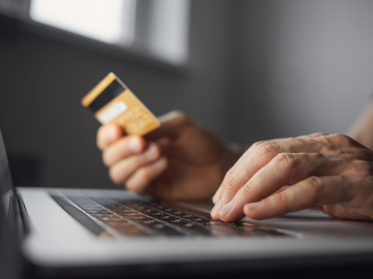 Person sidder med computer og betalingskort