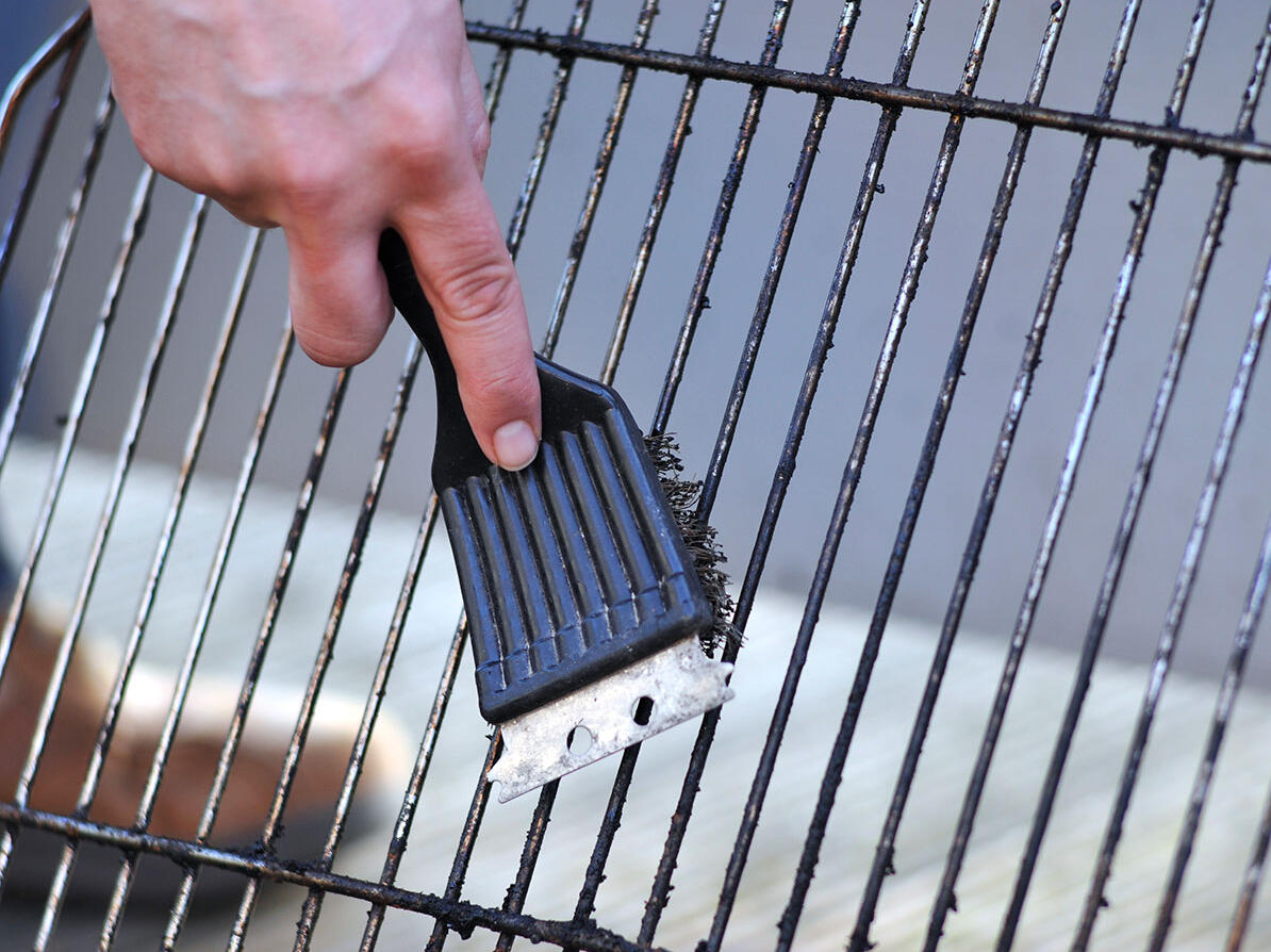 Person rengør grill og vedligeholder