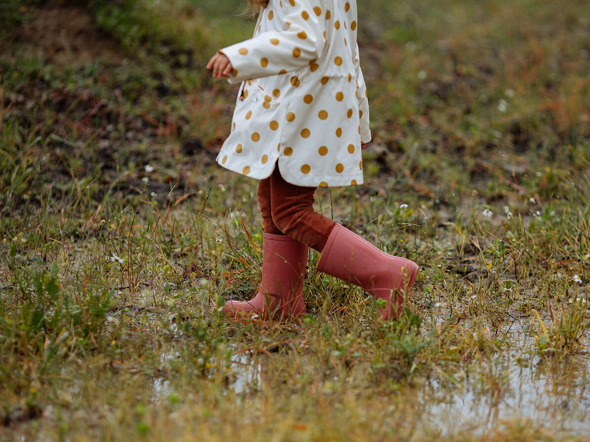 Barn går i et vådt område med gummistøvler på