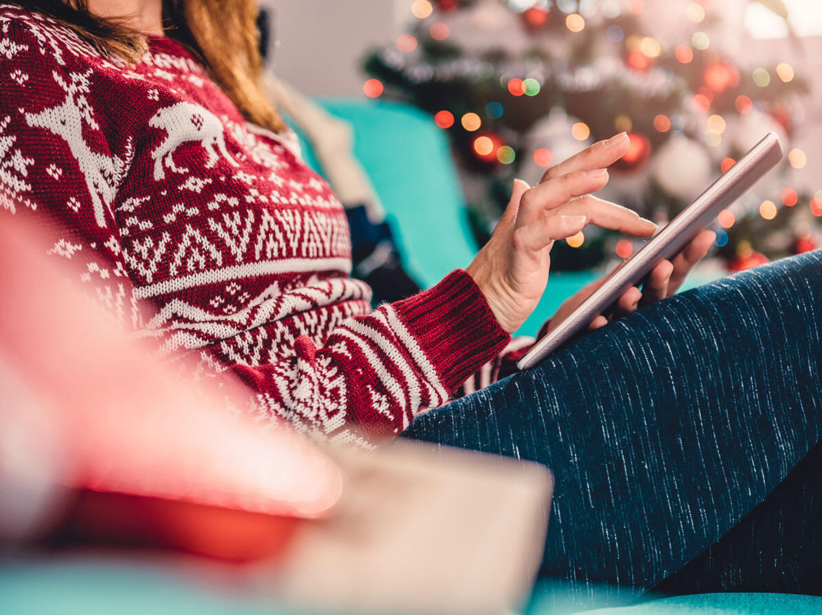 Kvinde sidder på tablet og shopper julegaver online.