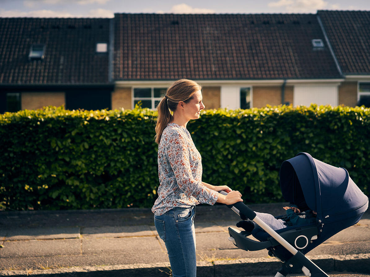 Kvinde går tur med baby i en kombivogn