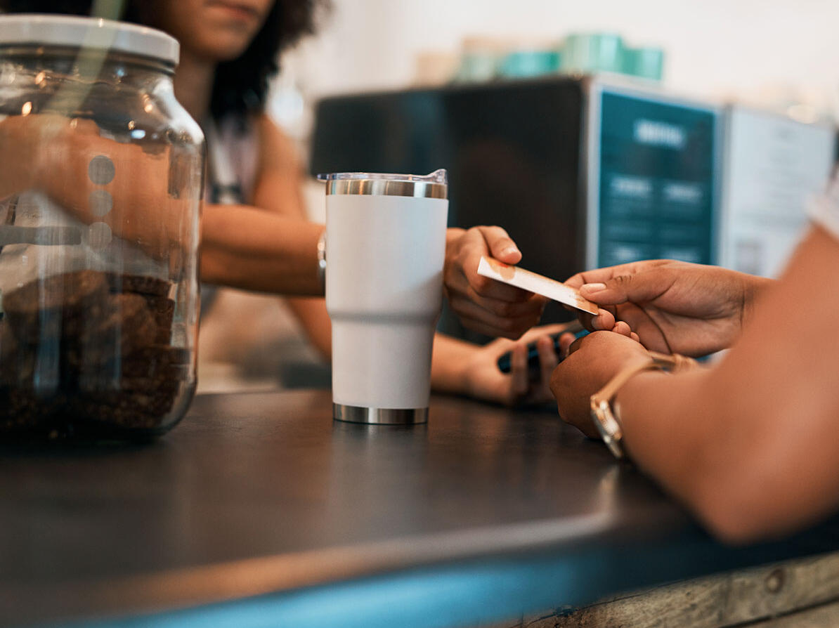 En person afleverer et medlemskort mens der købes kaffe