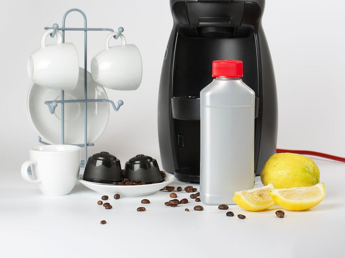 Espressomaskine, kapsler, citroner og kaffekopper 