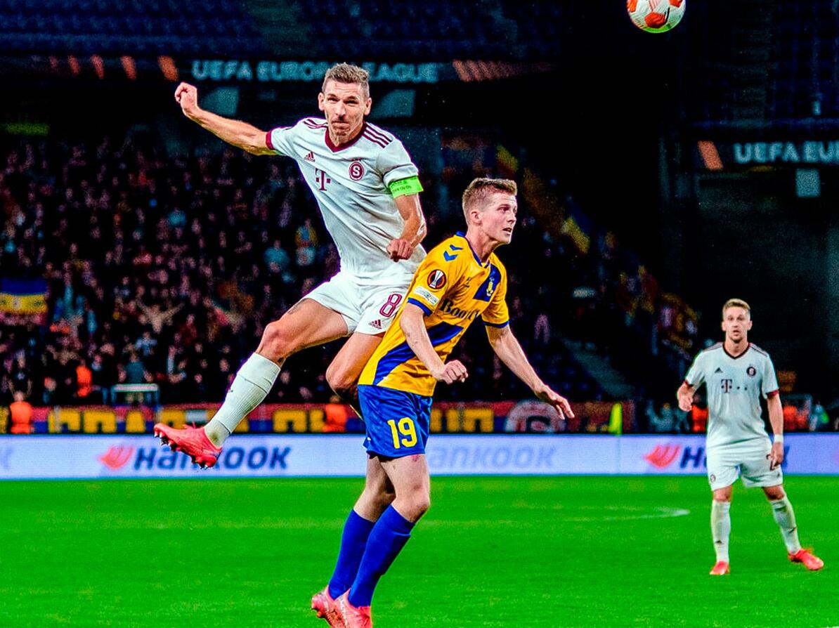 To fodboldspillere kæmper om bolden på et stadion