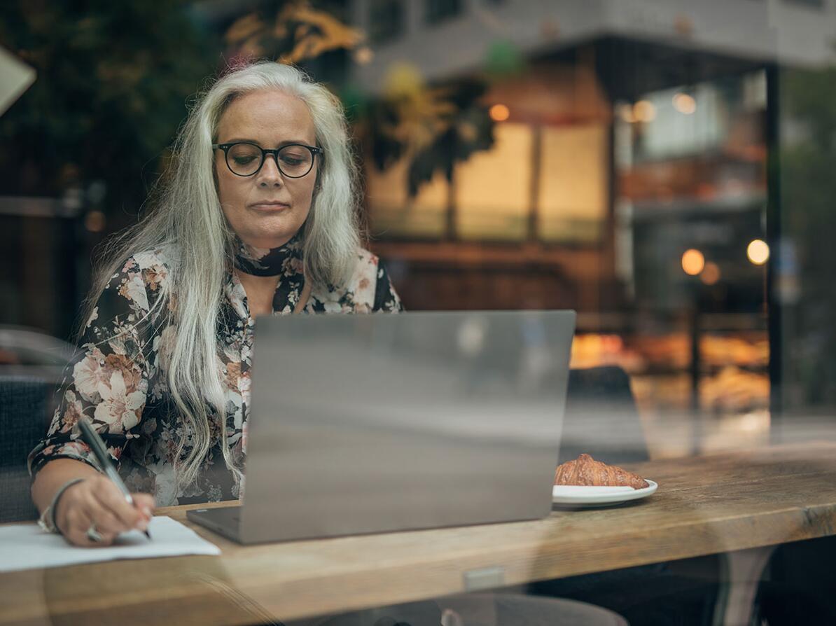 Kvinde sidder med sin computer på en cafe