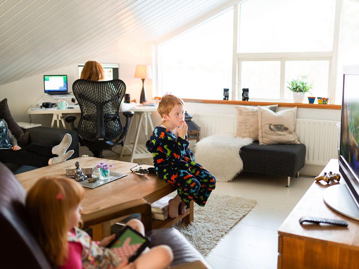 Børn der ser tv, og en person der sidder ved en computer