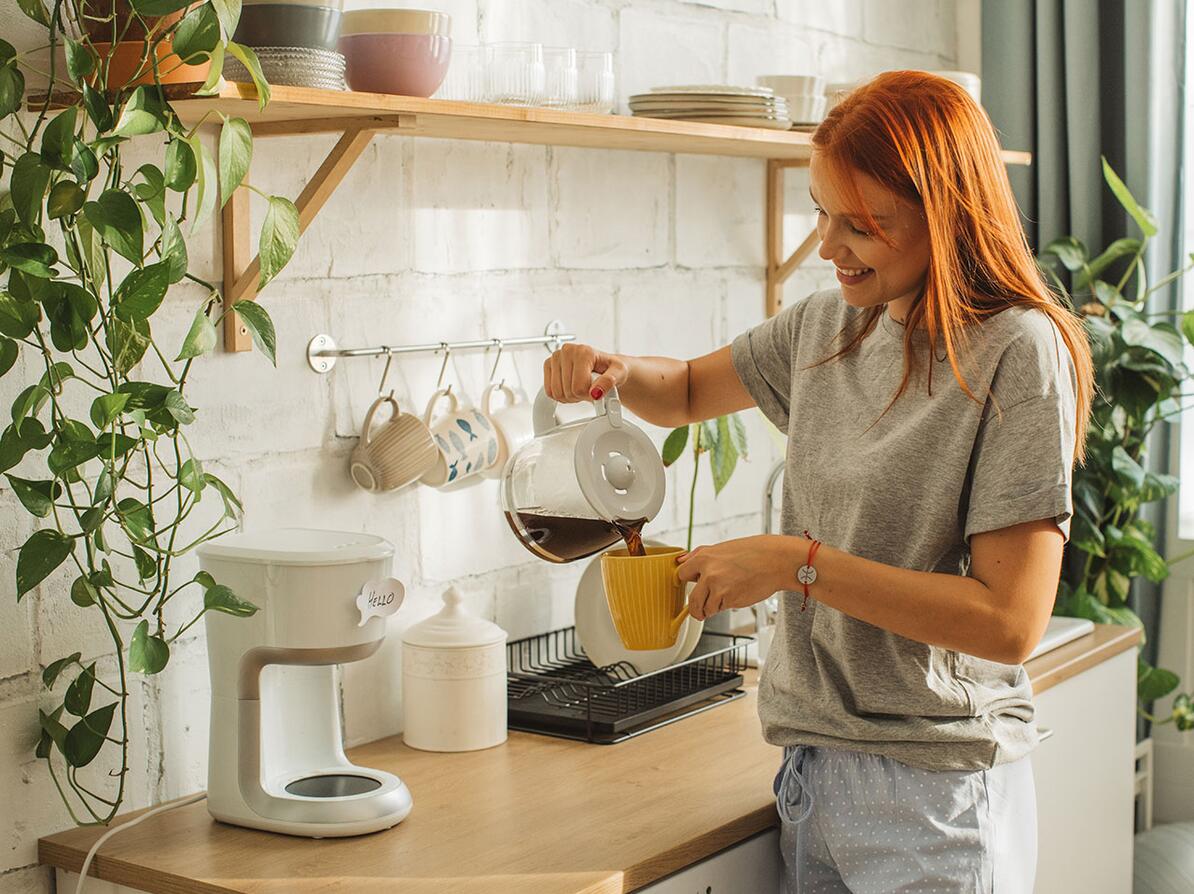 Person står og hælder kaffe op fra kaffemaskine
