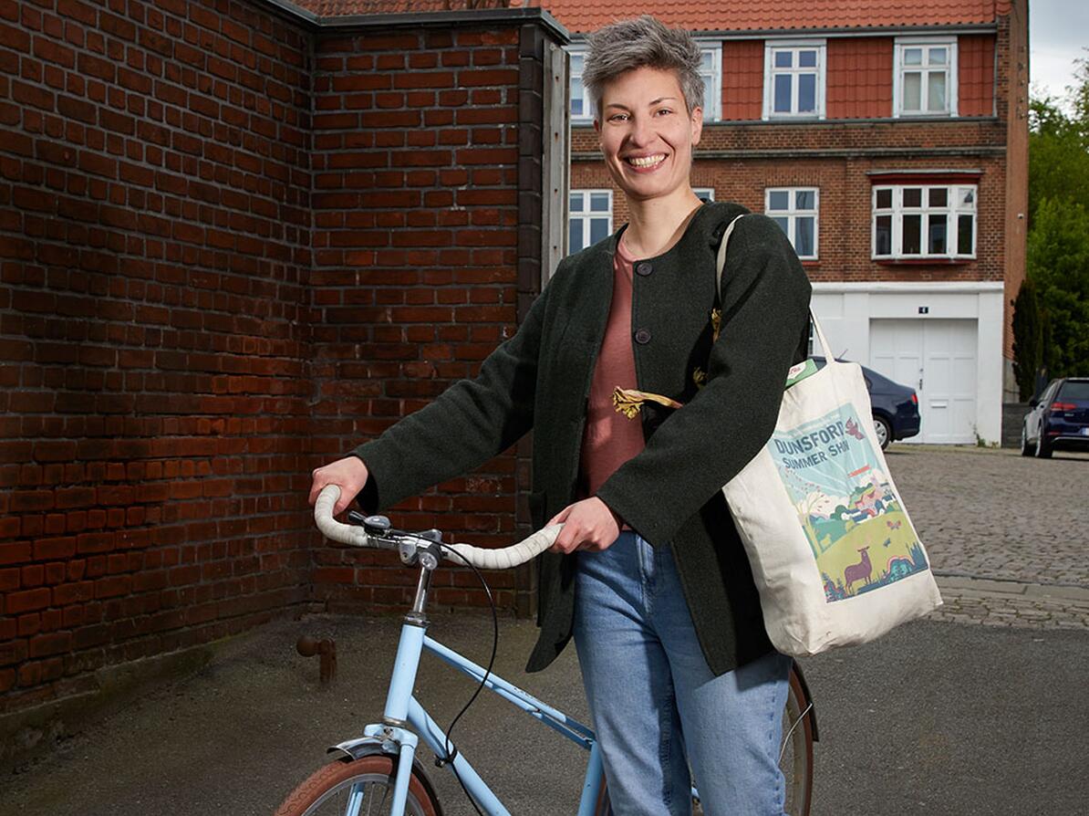 Kvinde står med sin cykel med stofnet over skulderen. Hun mener, at klima og sundhed hænger sammen. 