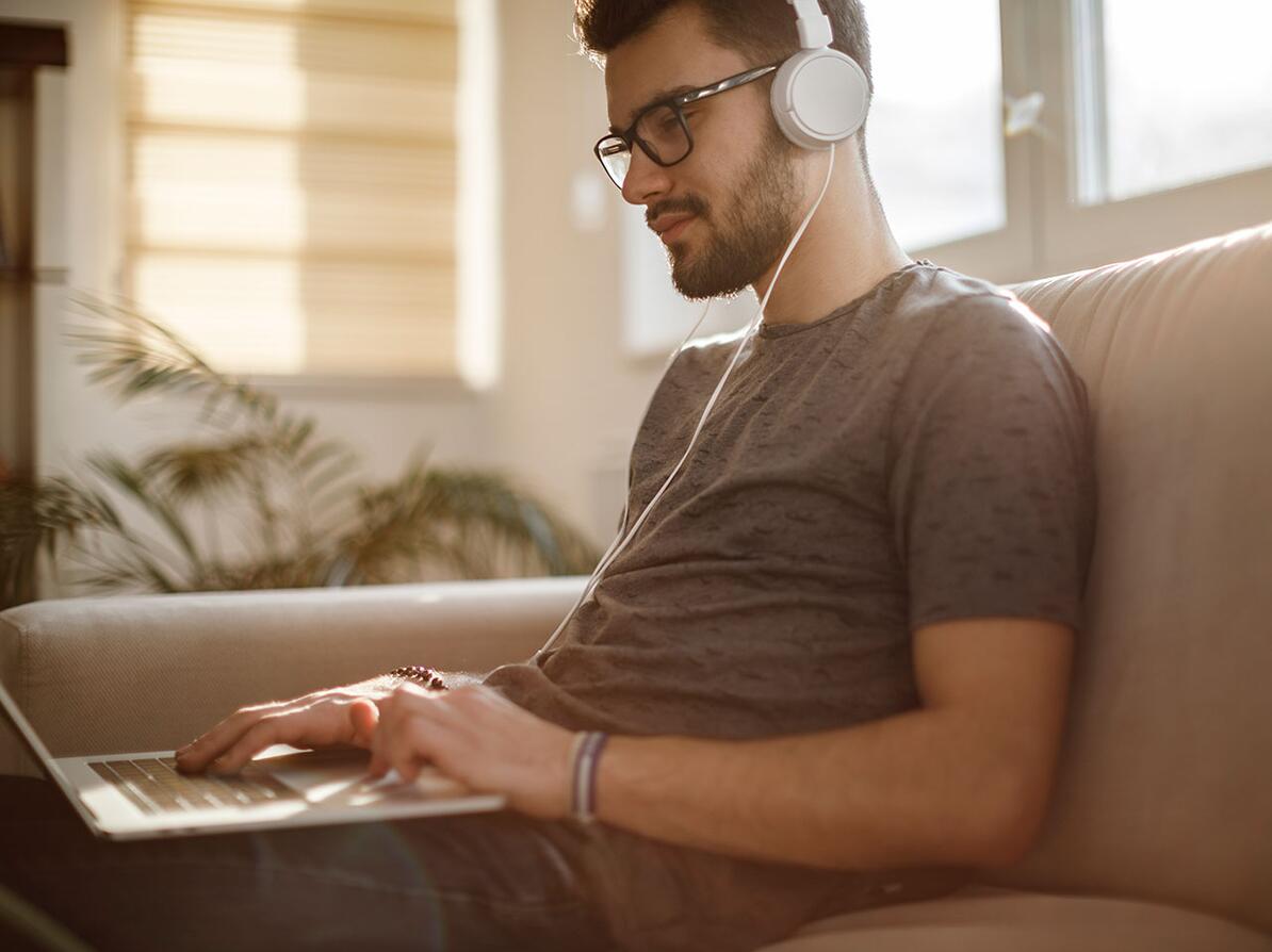 Mand sidder med sin computer og høretelefoner