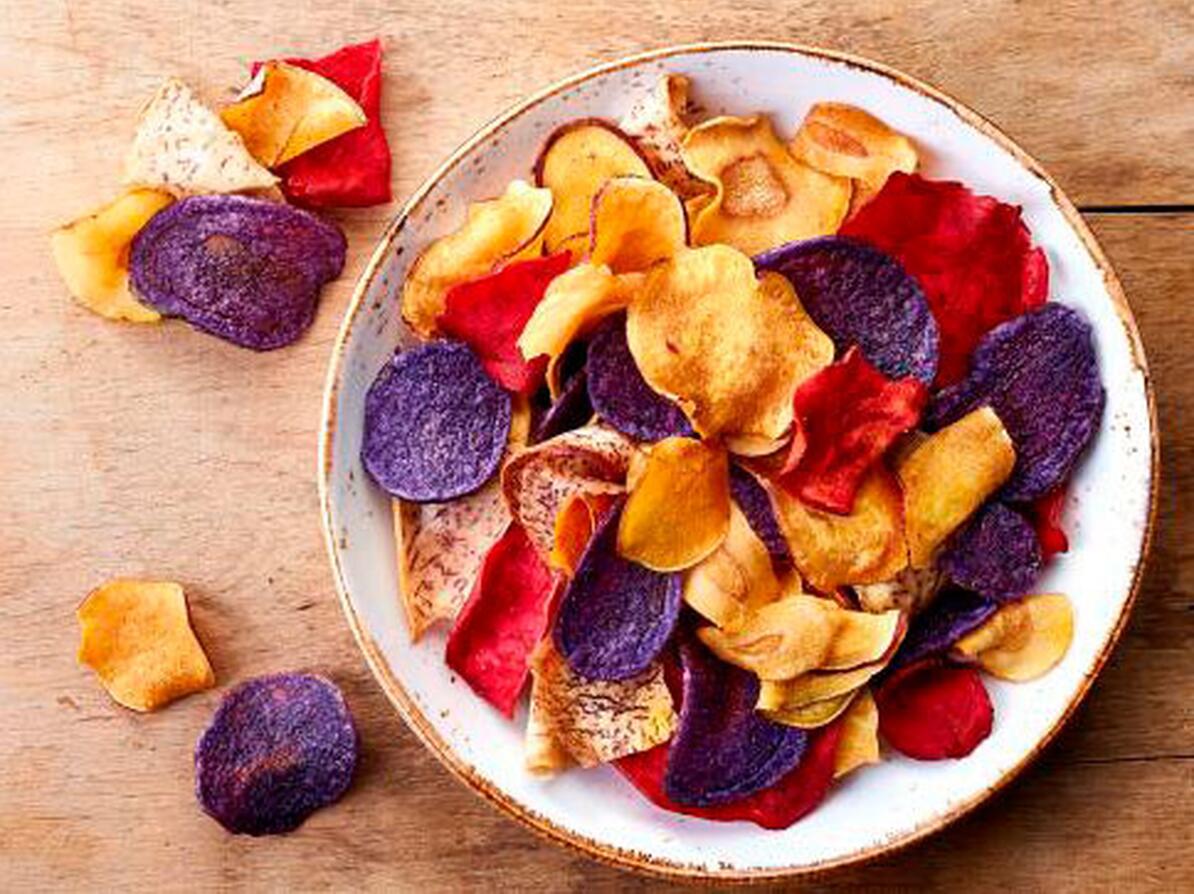 Skål med rodfrugt chips på et træbord.