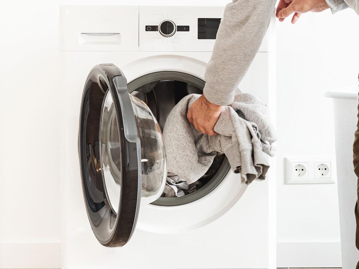 Person fylder tøj i vaskemaskine og tænker over hvad der er de bedste mærker