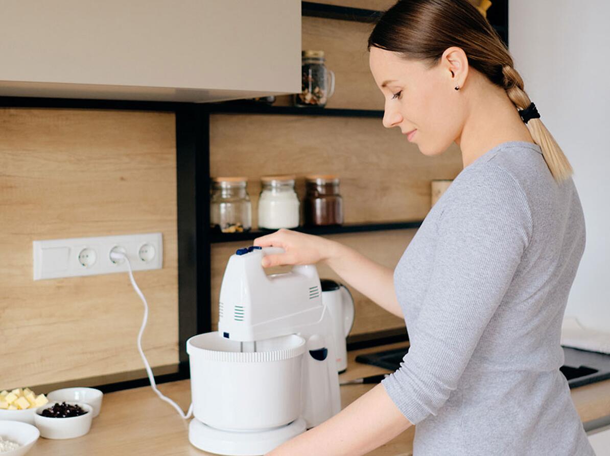 Person bruger håndmixer med stand til at lave mad