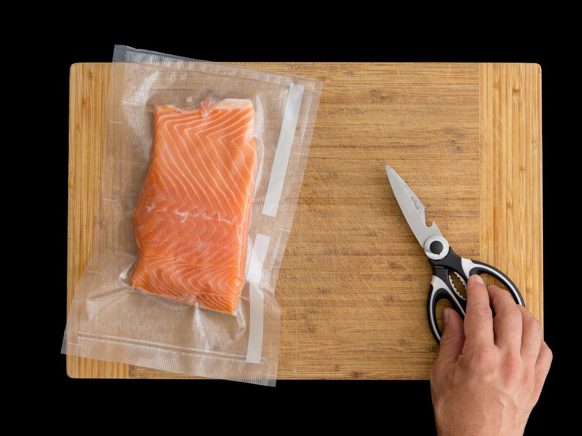 Vacuumpakket laks til sous vide på et skærebræt.