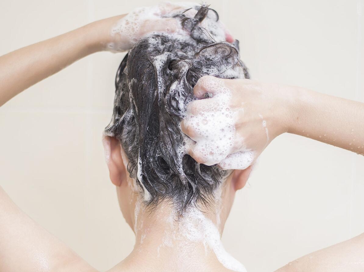 Kvinde vasker hår med shampoo