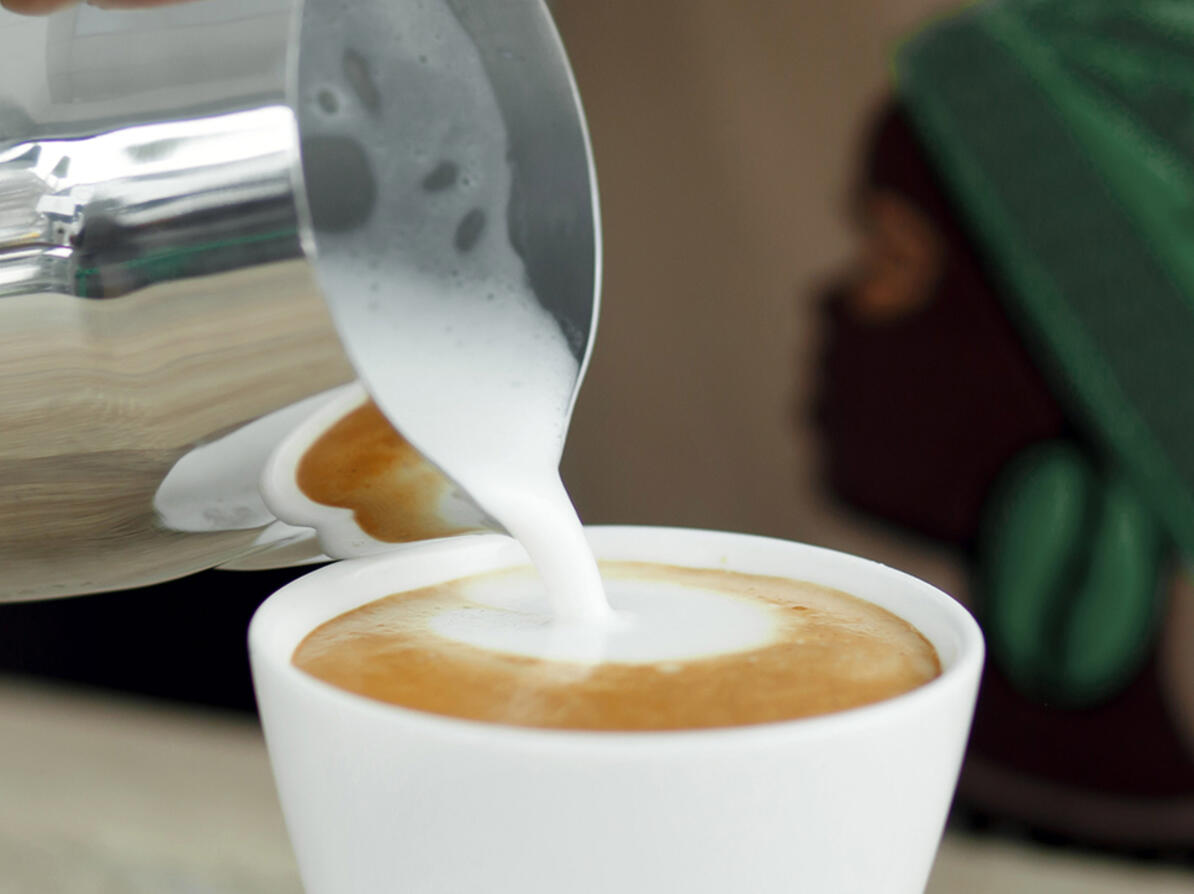Skummet mælk bliver hældt i kaffen