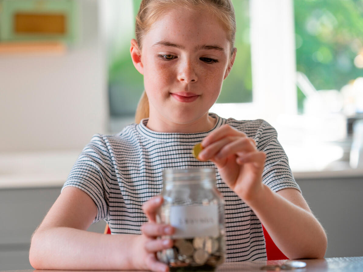 Barn putter penge i krus til lommepenge