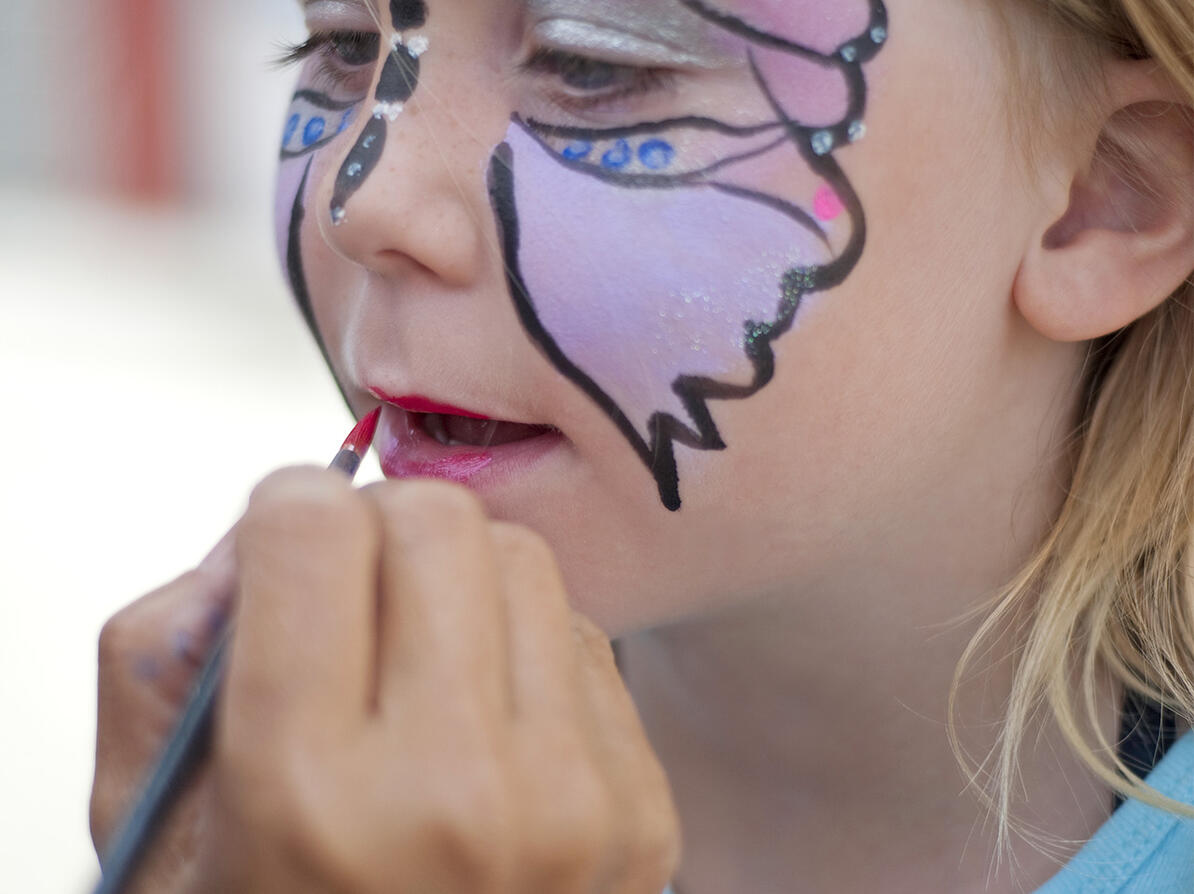 Pige får tegnet en sommerfugl i ansigtet