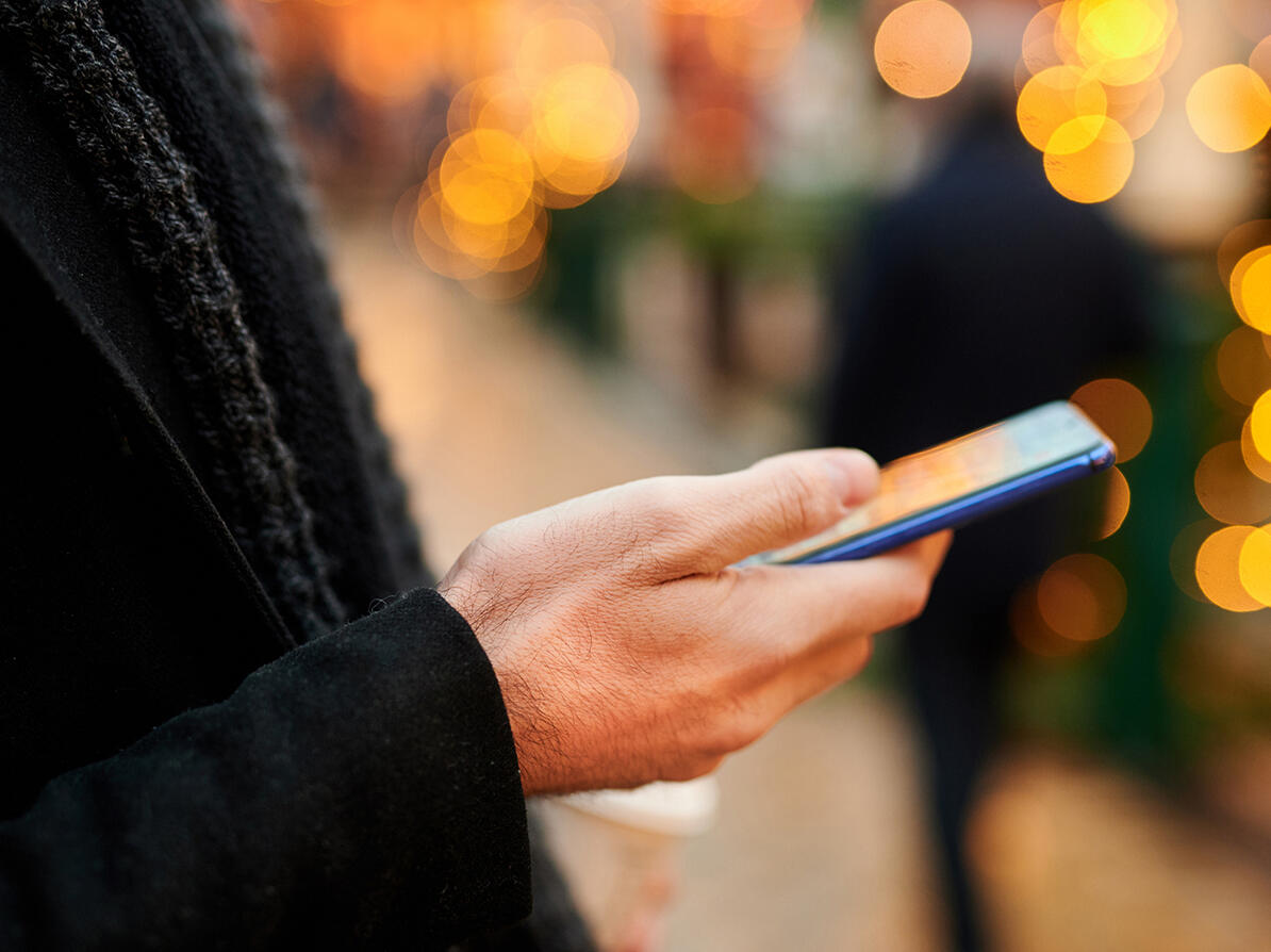 En hånd holder en smartphone udenfor 