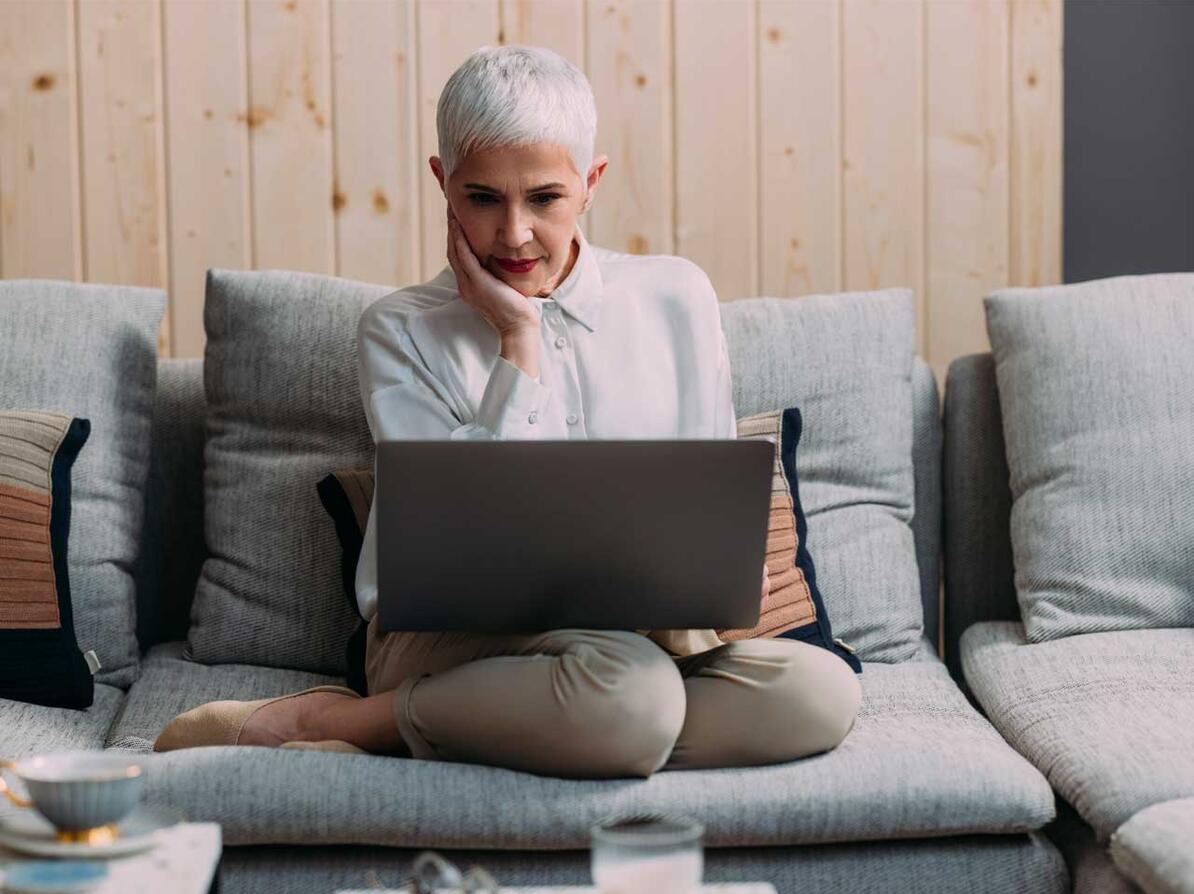 Kvinde på sofa kigger på computer