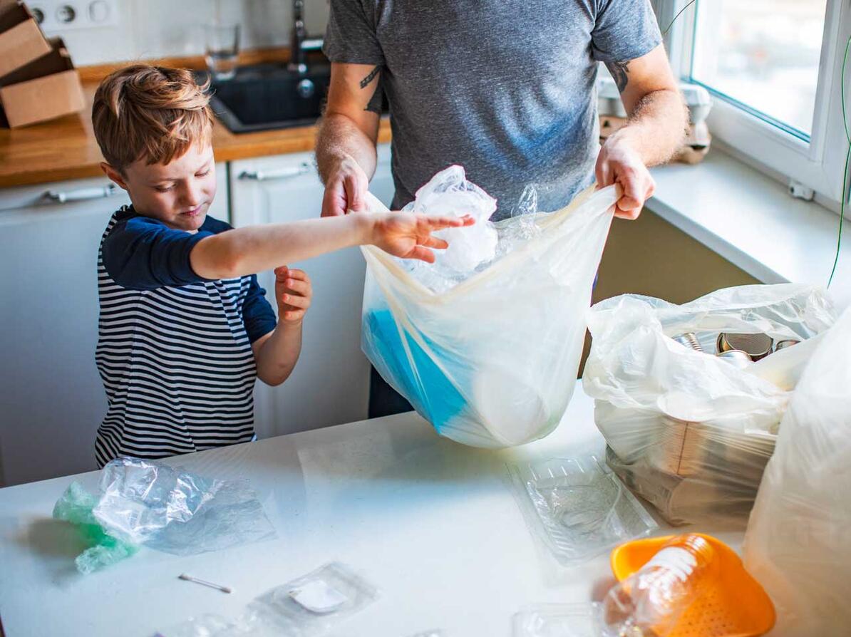 Dreng og mand sortere plastikaffald i køkkenet