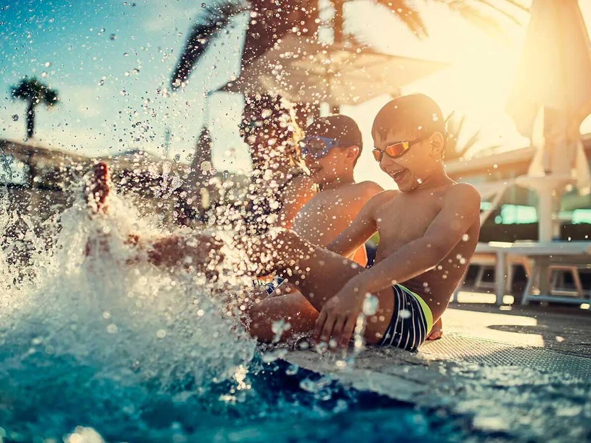 To børn er på badeferie og plasker i poolen.