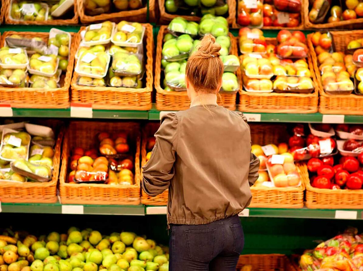 Kvinde kigger på væg med frugt og grøntsager der både er med og uden sprøjtemidler