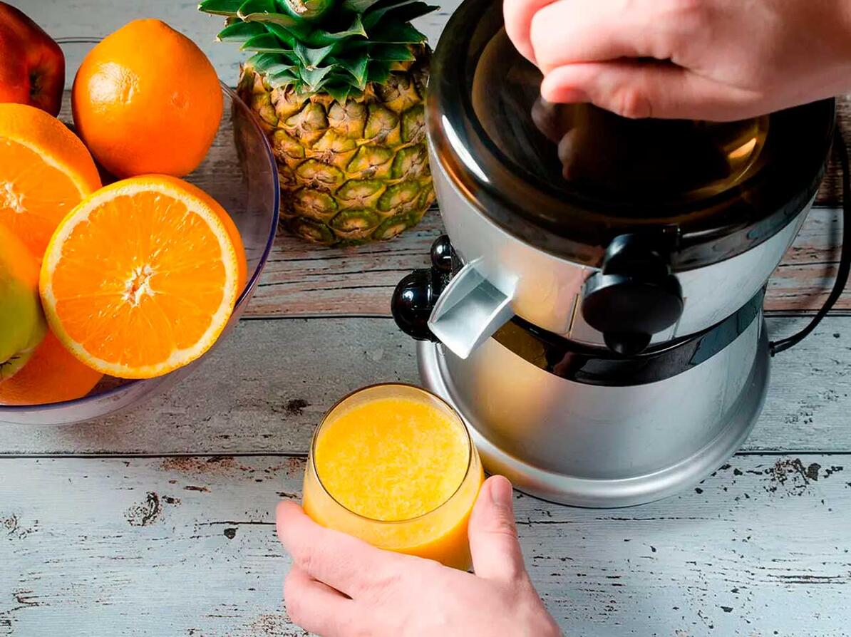 Saftpresser ved siden af frugt og appelsinjuice.
