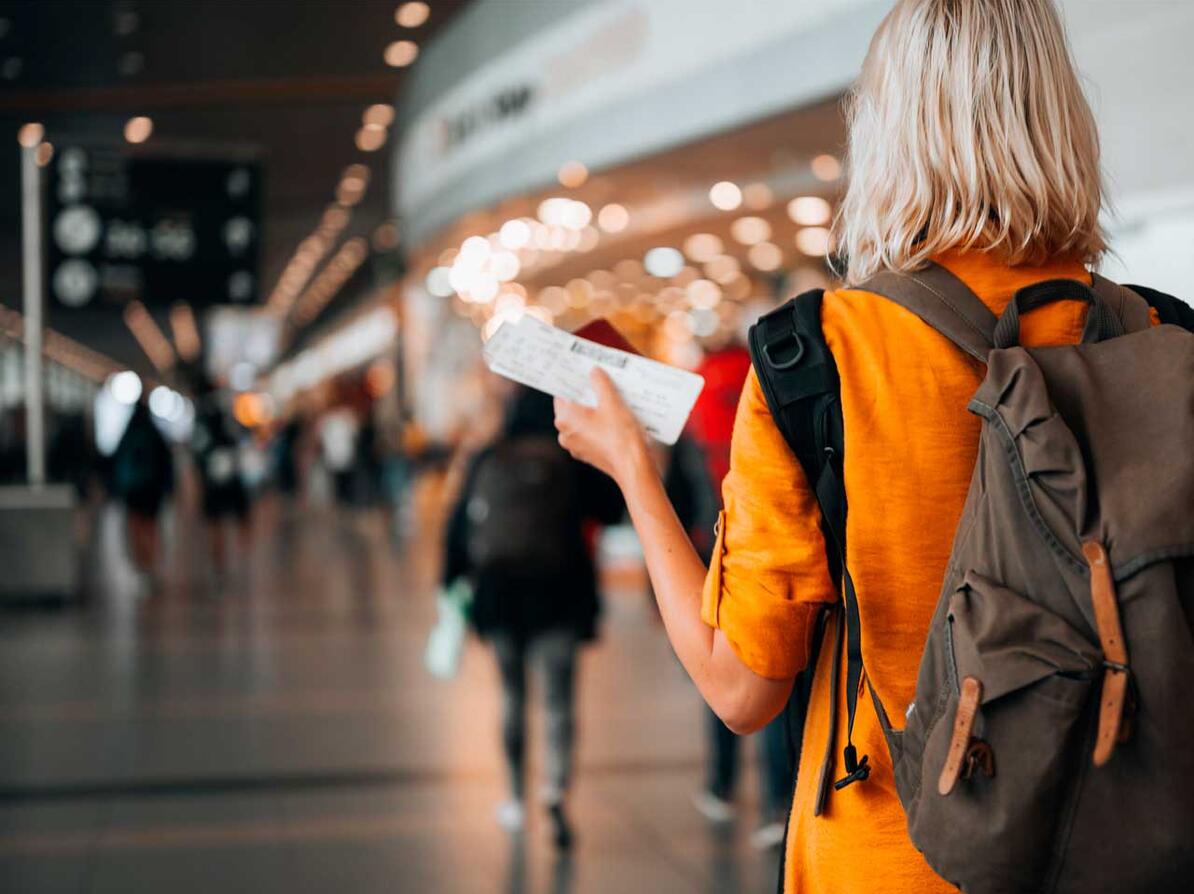 Kvinde i lufthaven med boardringpas på vej ud at flyve