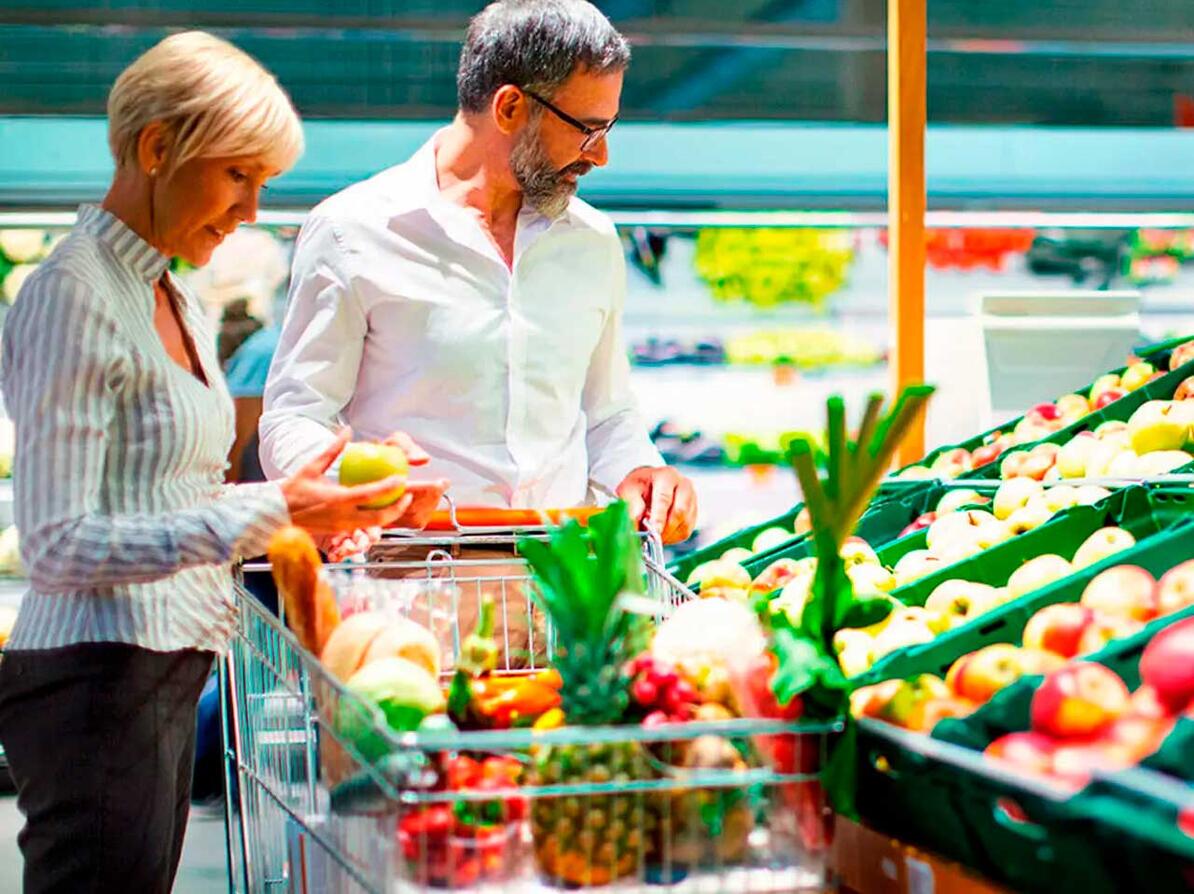 Par kigger i supermarked på frugter både med og uden sprøjtemidler