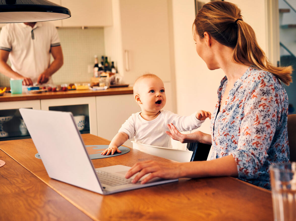 Kvinde sidder med computeren og taler med sit barn