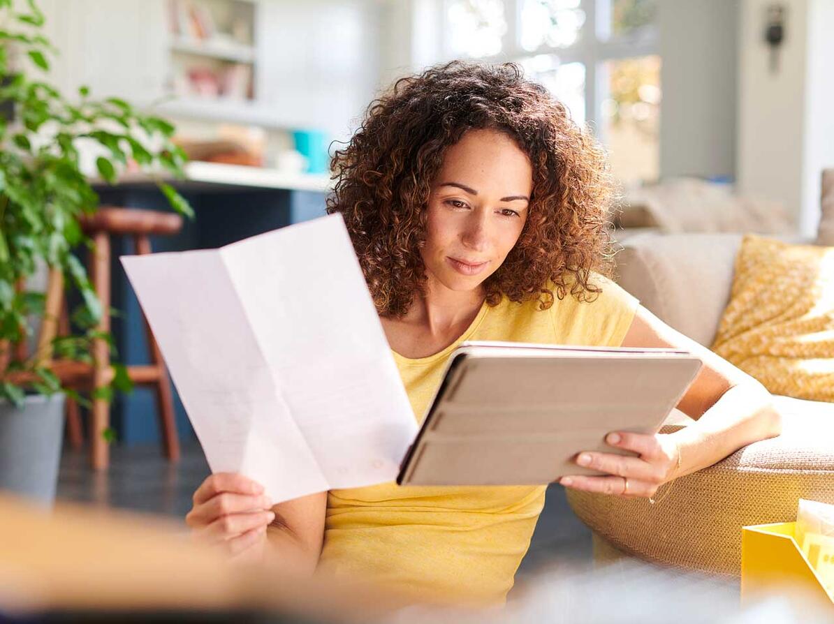 kvinde kigger på papir og tablet med informationer om en investerinsforening