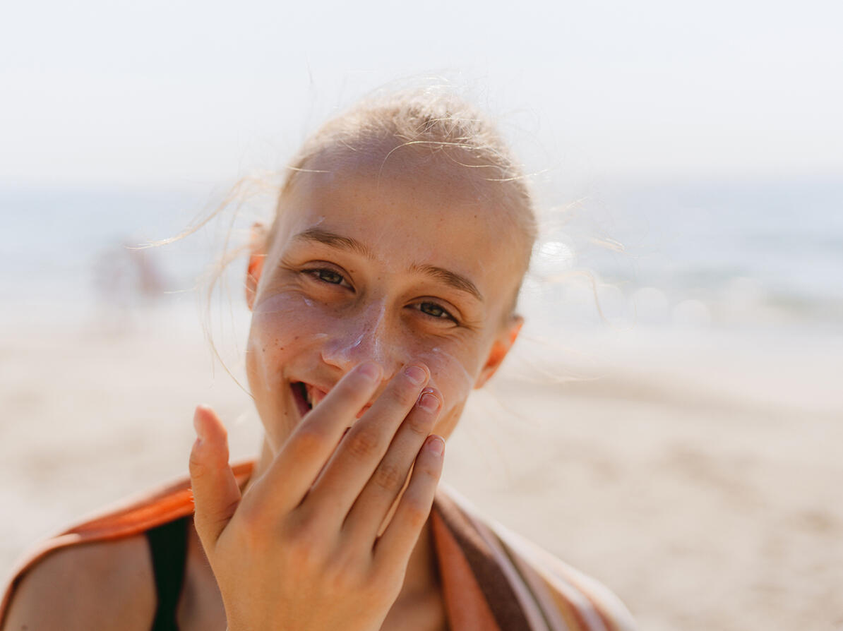 nærbillede af teenagepige der smører solcreme i ansigtet