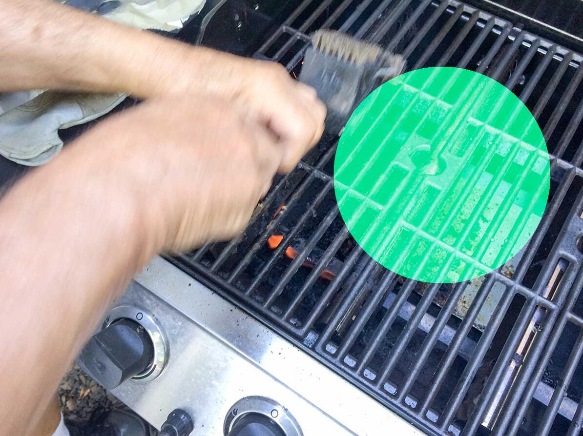 sådan vedligeholder du din gasgrill - person der renser grillrist