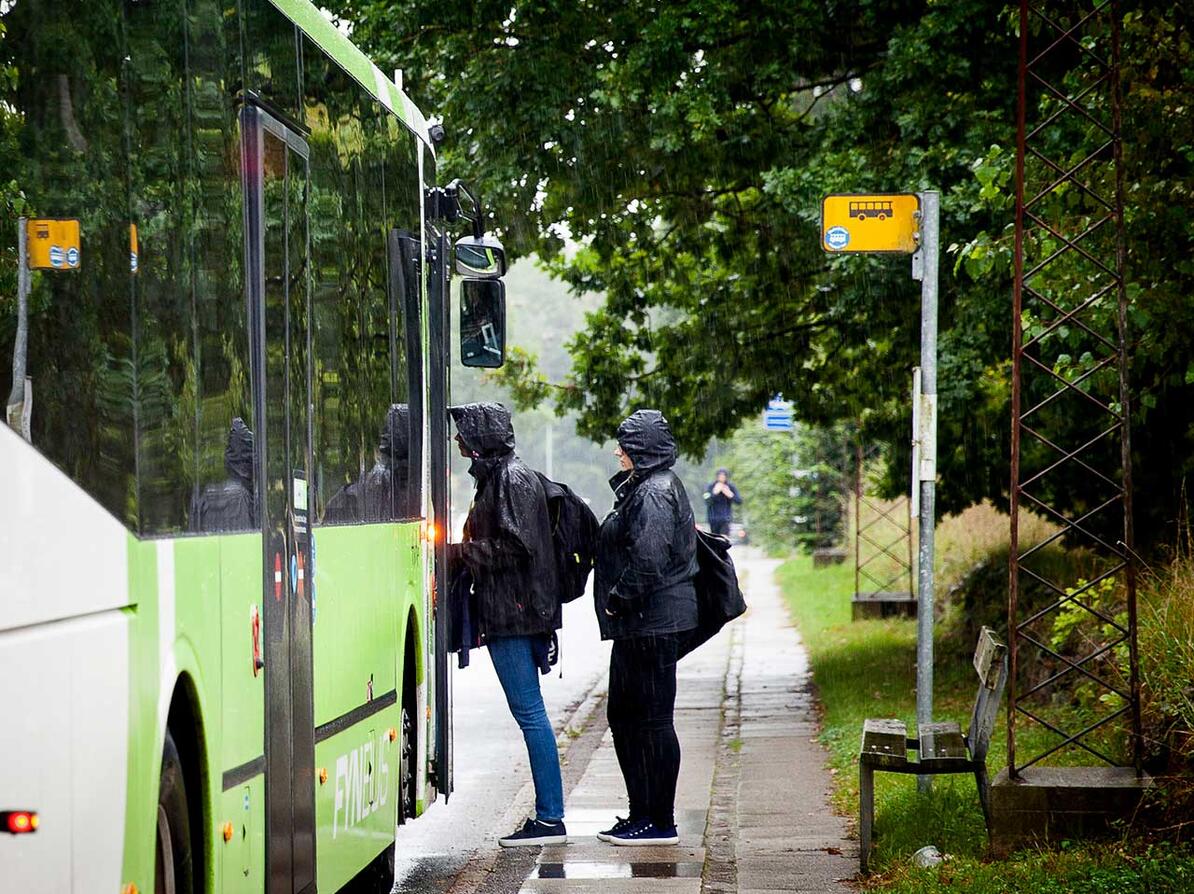 To passagerer står på bussen i regnvejr