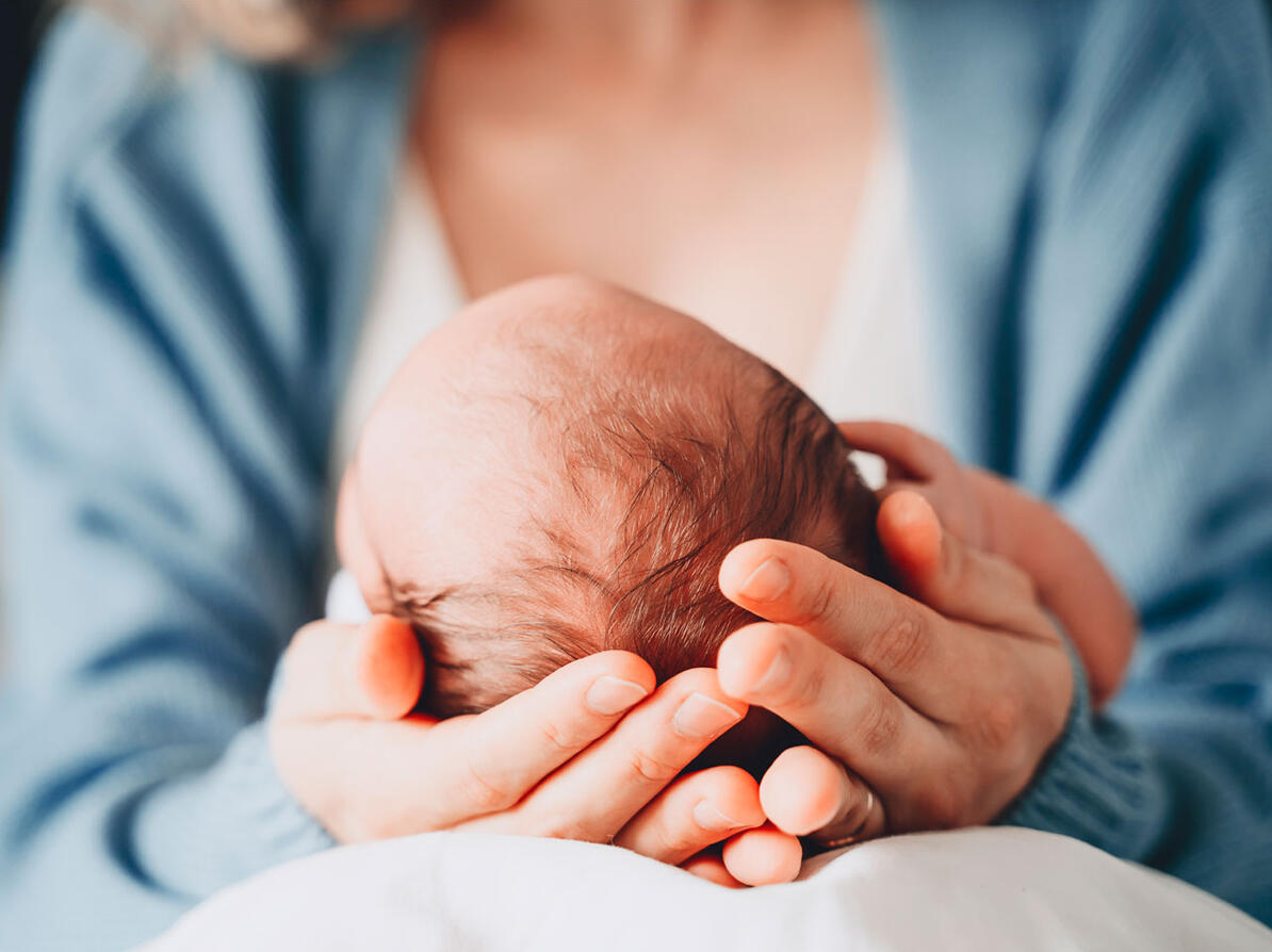 Spædbarn i armende på kvinde