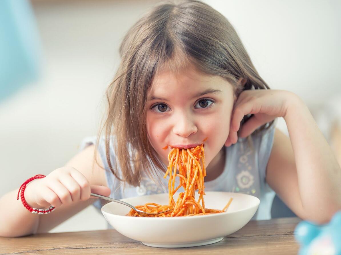 Pige spiser spaghetti med sovs